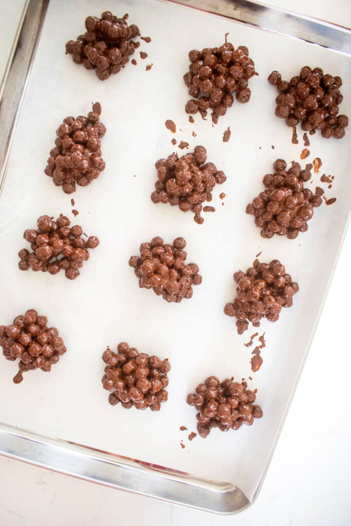 puppy chow candy clusters on a baking sheet on a marble counter.