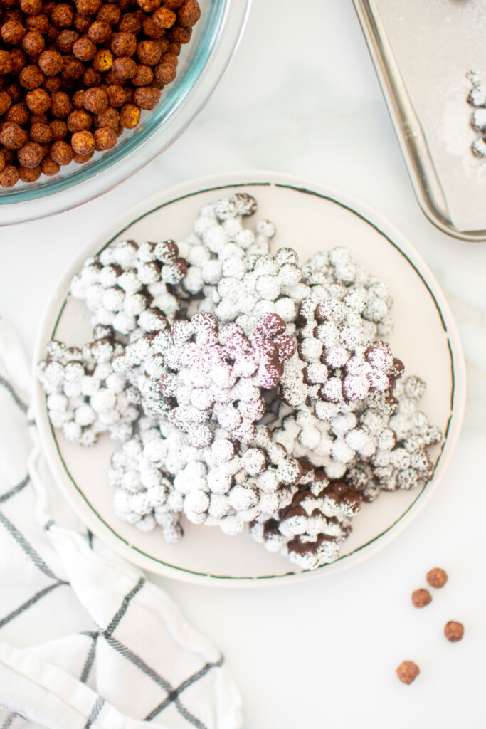 puppy chow candy clusters on a plate on a marble countertop.