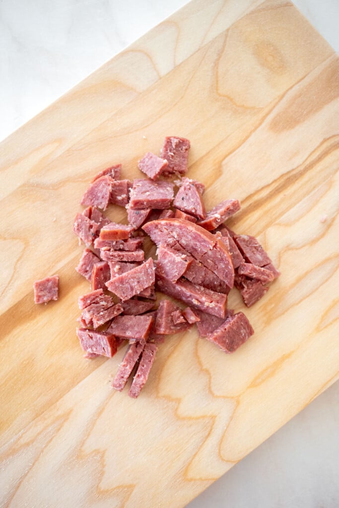 diced summer sausage on a wood cutting board.