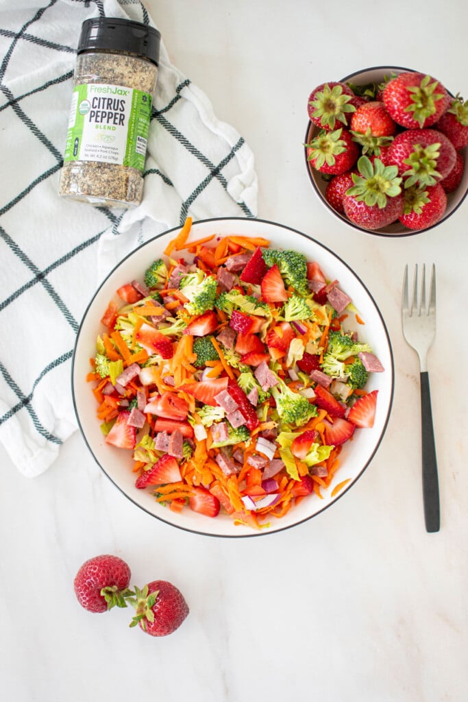 strawberry balsamic broccoli salad without dressing in a white bowl on a marble countertop.