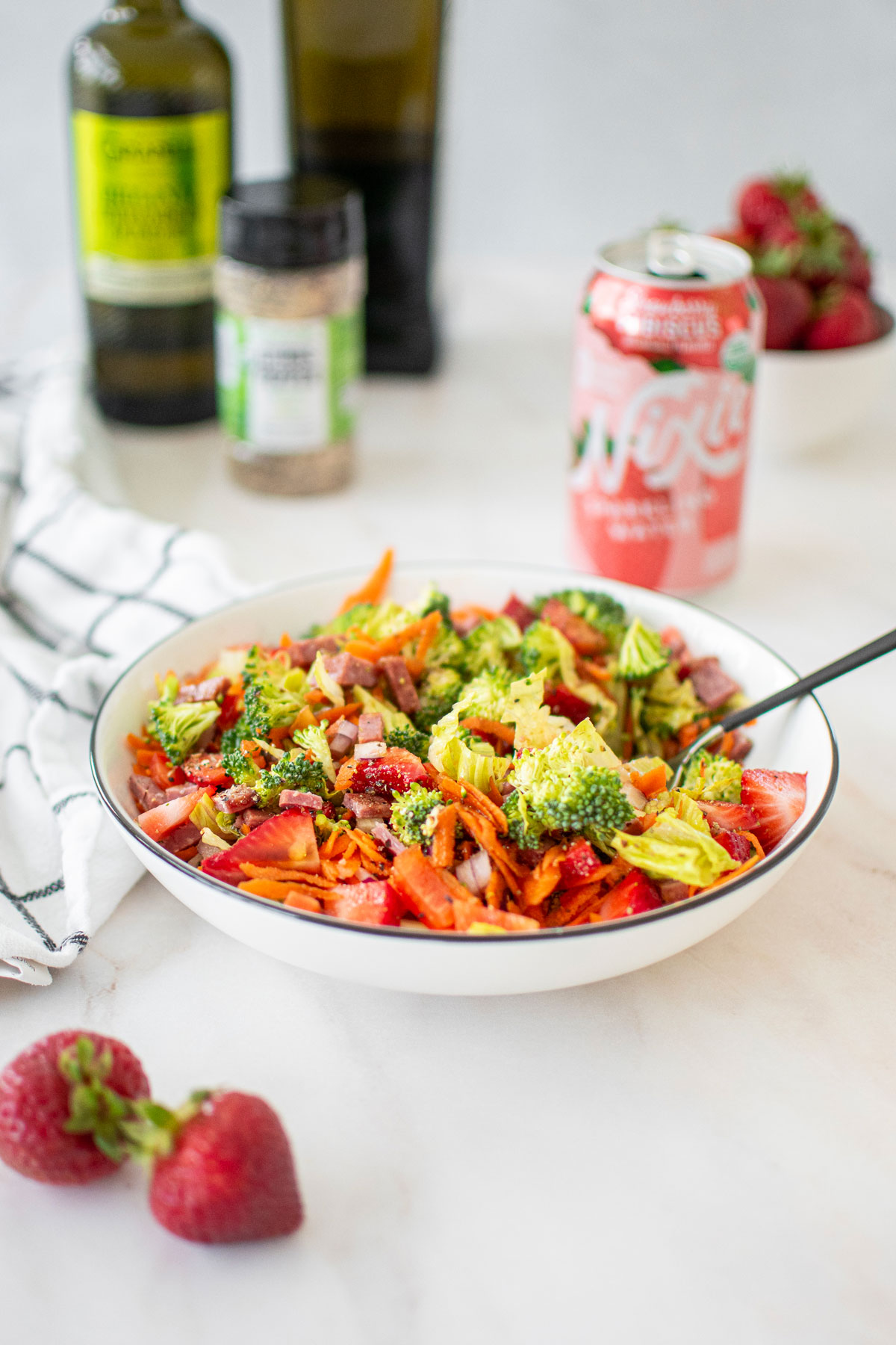 strawberry balsamic broccoli salad in a white bowl on a marble countertop with a fork in it.
