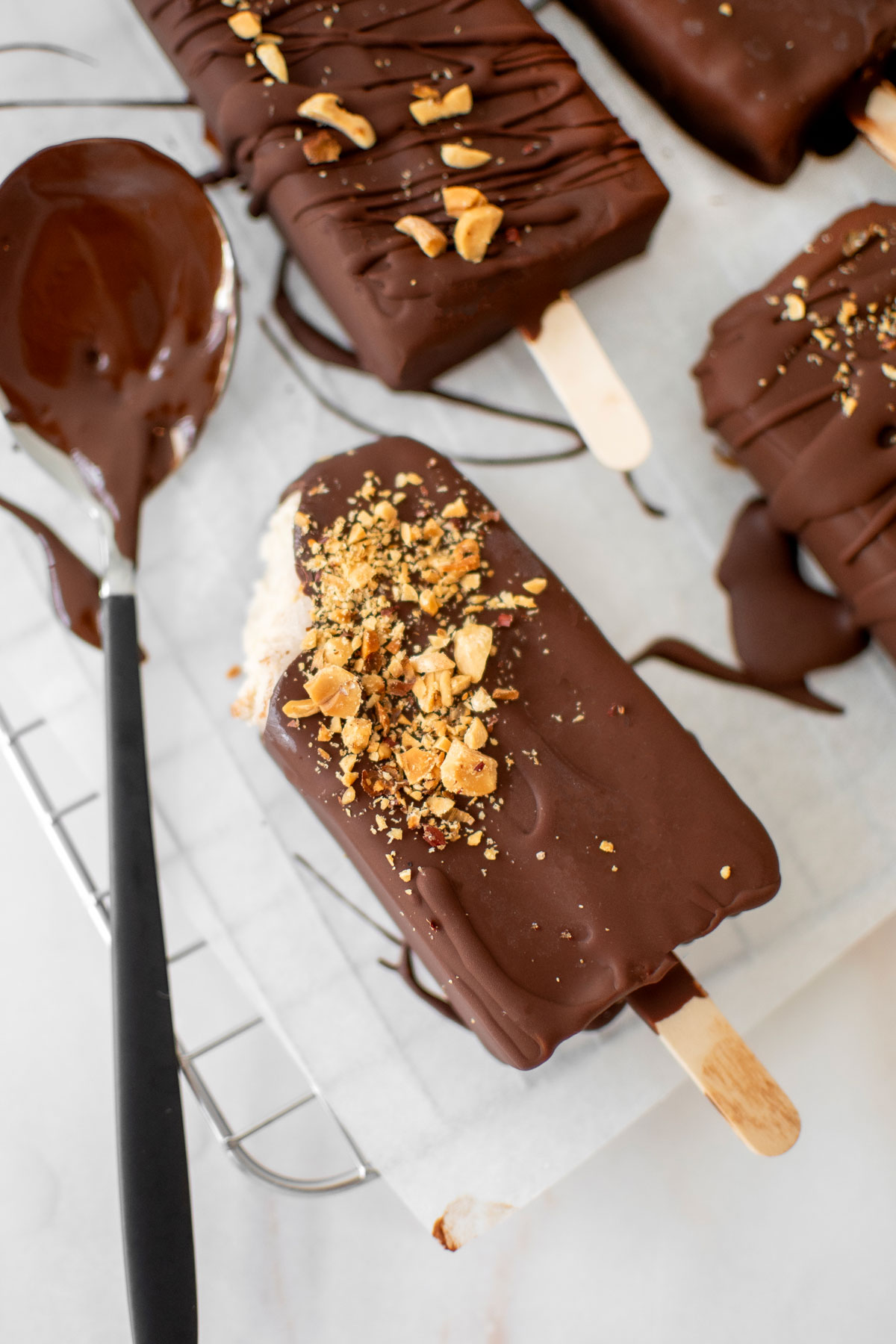 vegan chocolate peanut butter ice cream bar with a bite taken out on parchment paper.