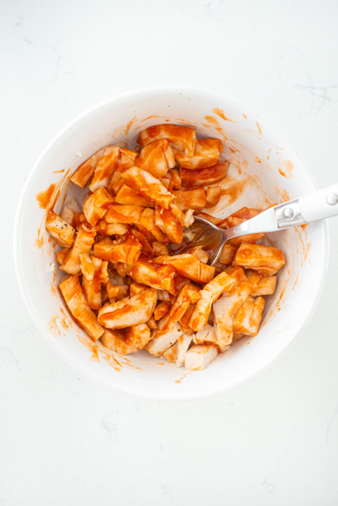 bbq chicken chopped into small pieces in a white bowl on a white marble counter.