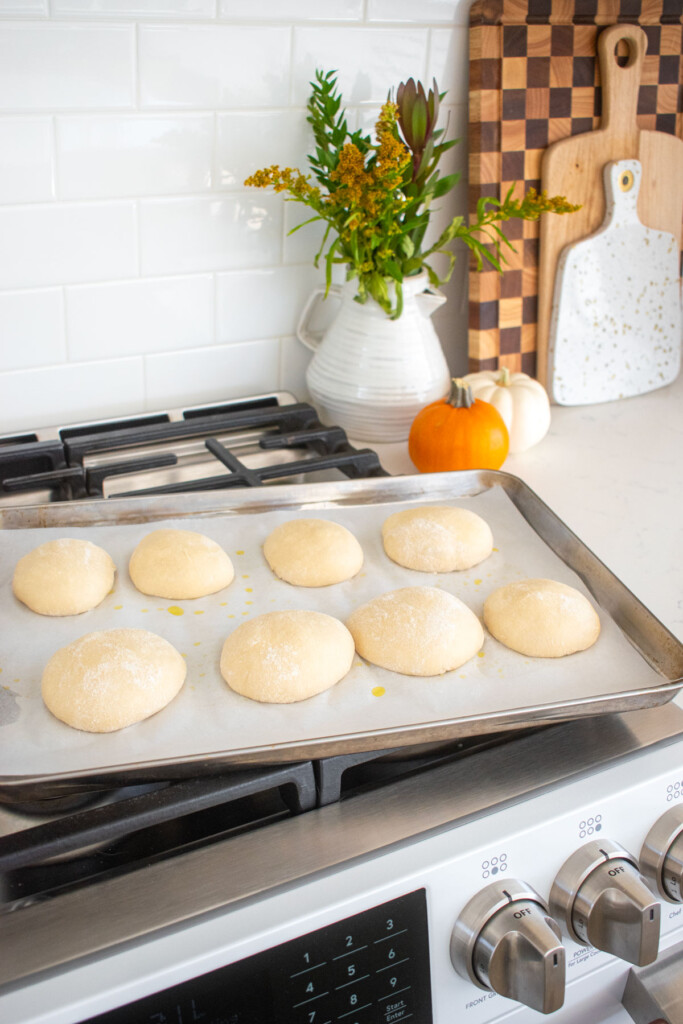 bagel dough balls on a baking sheet on the stovetop.