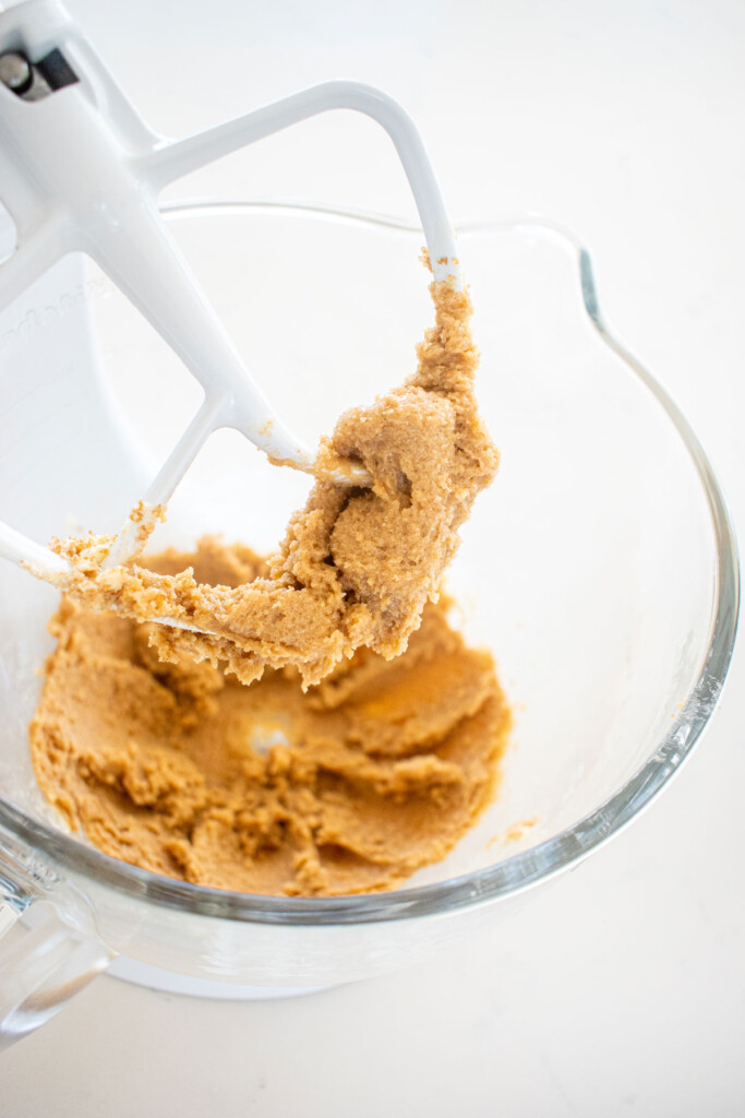creamed butter and sugar in a glass mixing bowl on a white marble counter.
