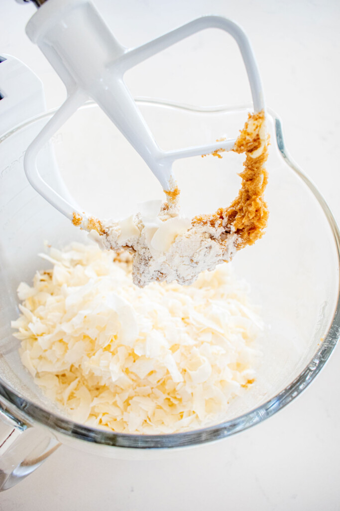 ingredients for coconut milk chocolate chunk cookie dough in a glass mixing bowl on a marble counter.