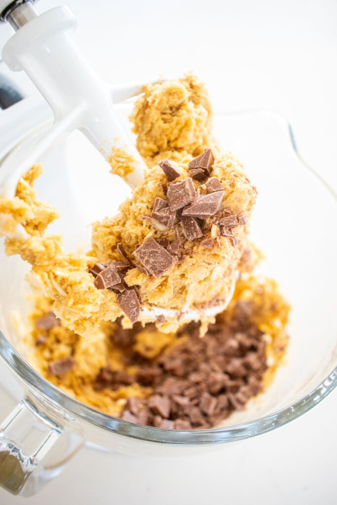 ingredients for coconut milk chocolate chunk cookie dough in a glass mixing bowl on a marble counter.