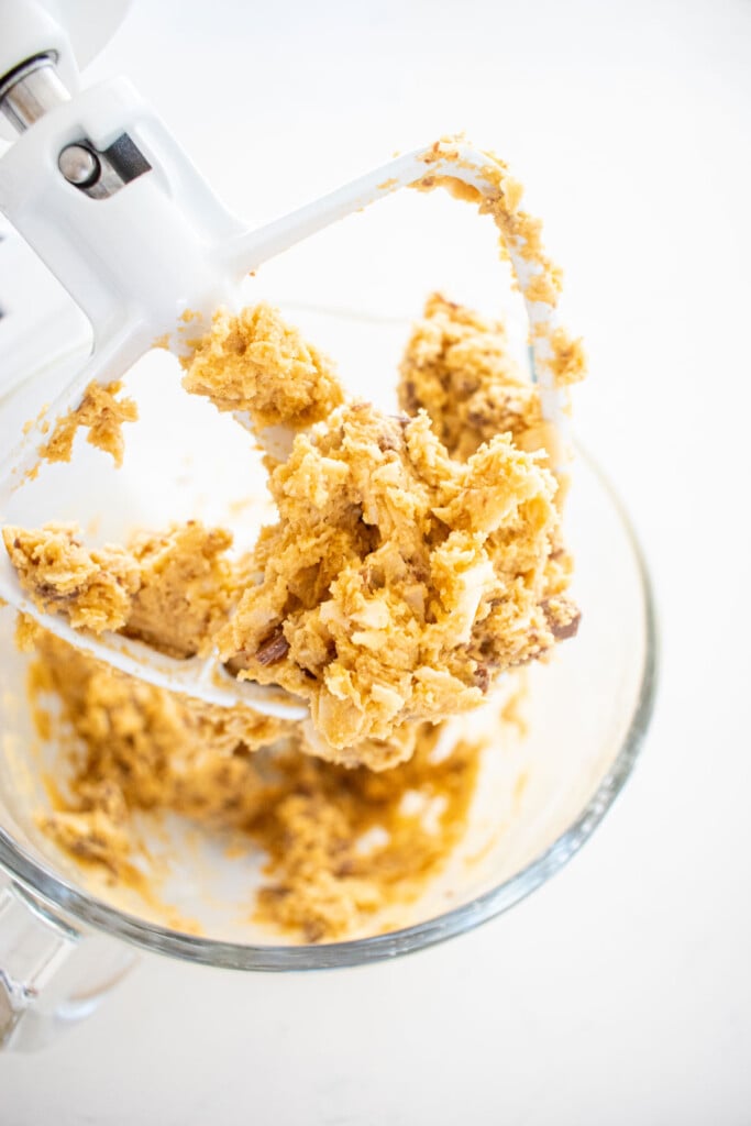 coconut milk chocolate chunk cookie dough in a glass mixing bowl on a marble counter.