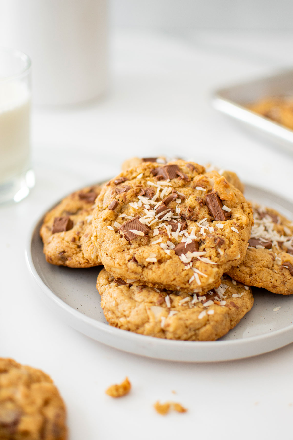 plate of coconut milk chocolate chunk cookies on a white marble counter with a glass of milk.