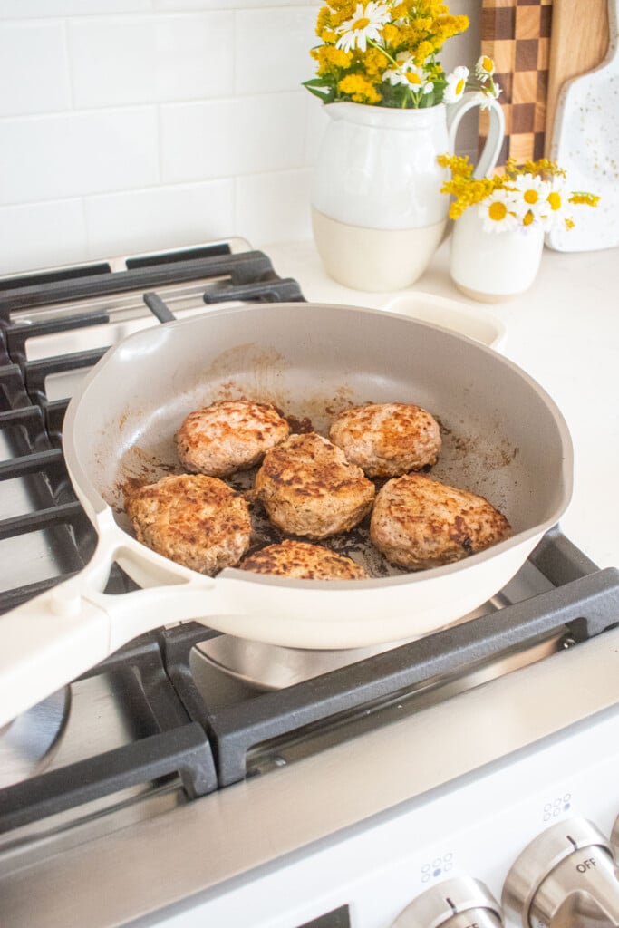 maple turkey breakfast sausages being cooked in a skillet on the stovetop.