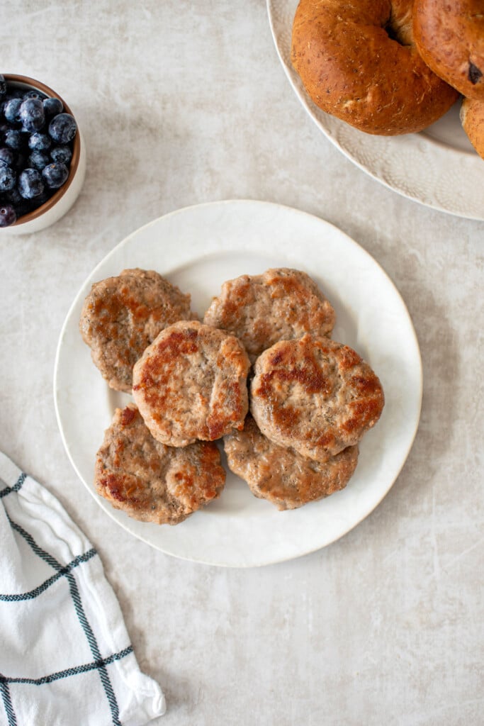 maple turkey breakfast sausages on a plate with bagels and blueberries on the side.