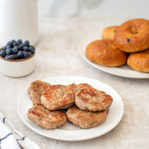 maple turkey breakfast sausages on a plate with bagels and blueberries on the side.