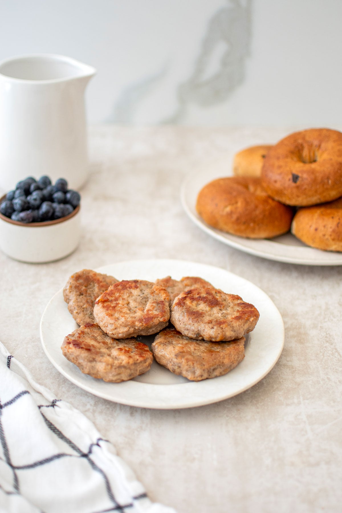 maple turkey breakfast sausages on a plate with bagels and blueberries on the side.