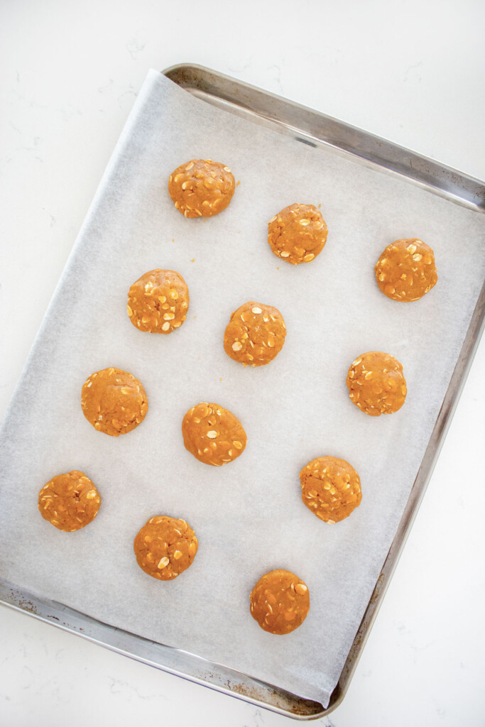 peanut butter dog cookie dough on a baking sheet on a white marble countertop.