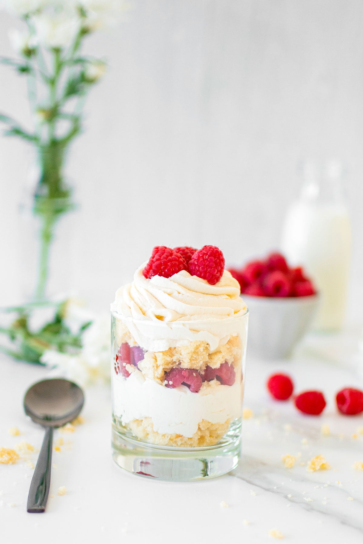 raspberry whipped cream cake jar with fresh raspberries on a white marble counter.