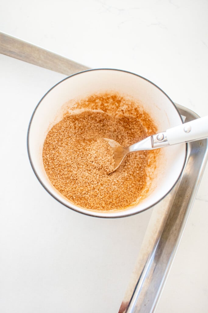cinnamon and sugar mixed together in a small bowl with a spoon a baking sheet.