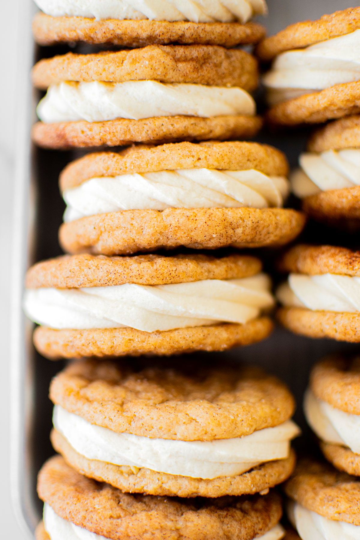 snickerdoodle sandwich cookies on a baking sheet on a white marble counter.