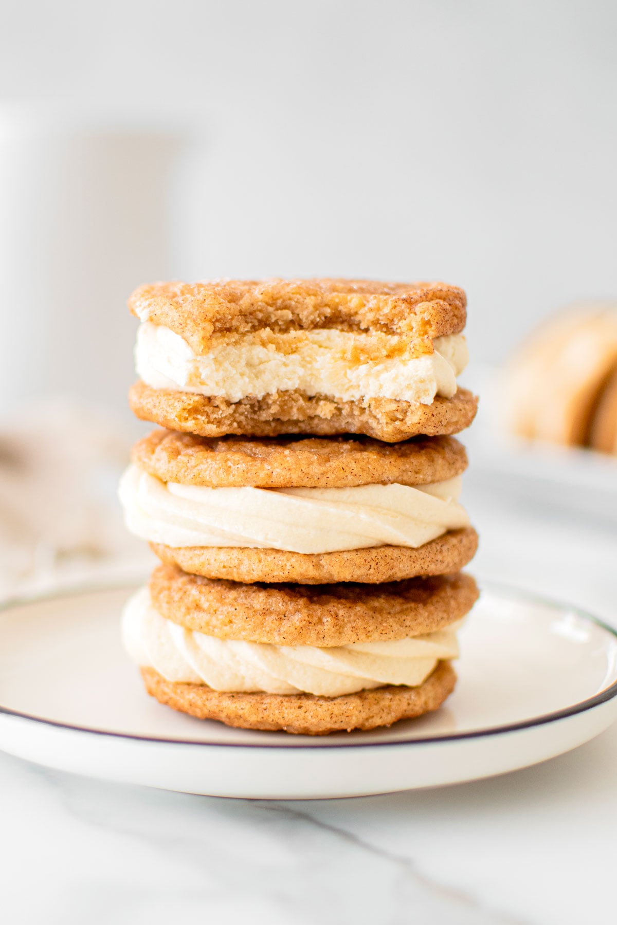 a stack of snickerdoodle sandwich cookies on a plate and the top cooking has a bite taken out.