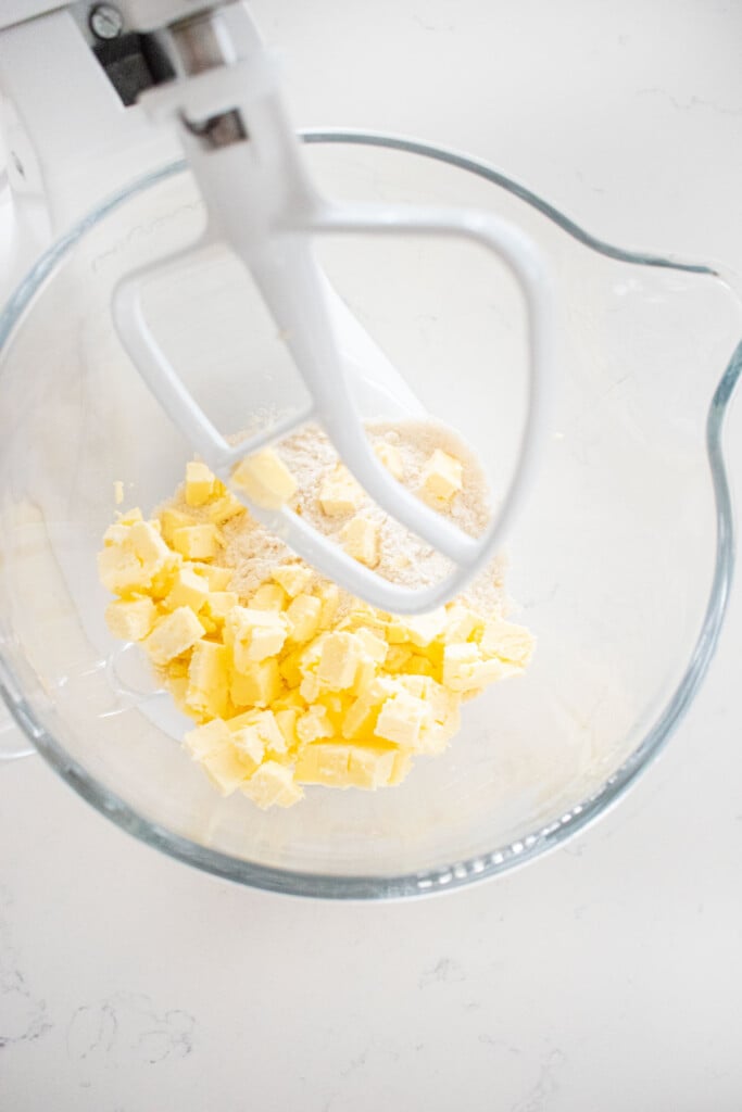 ingredients for sourdough pie crust in a glass mixing bowl on a white marble counter.