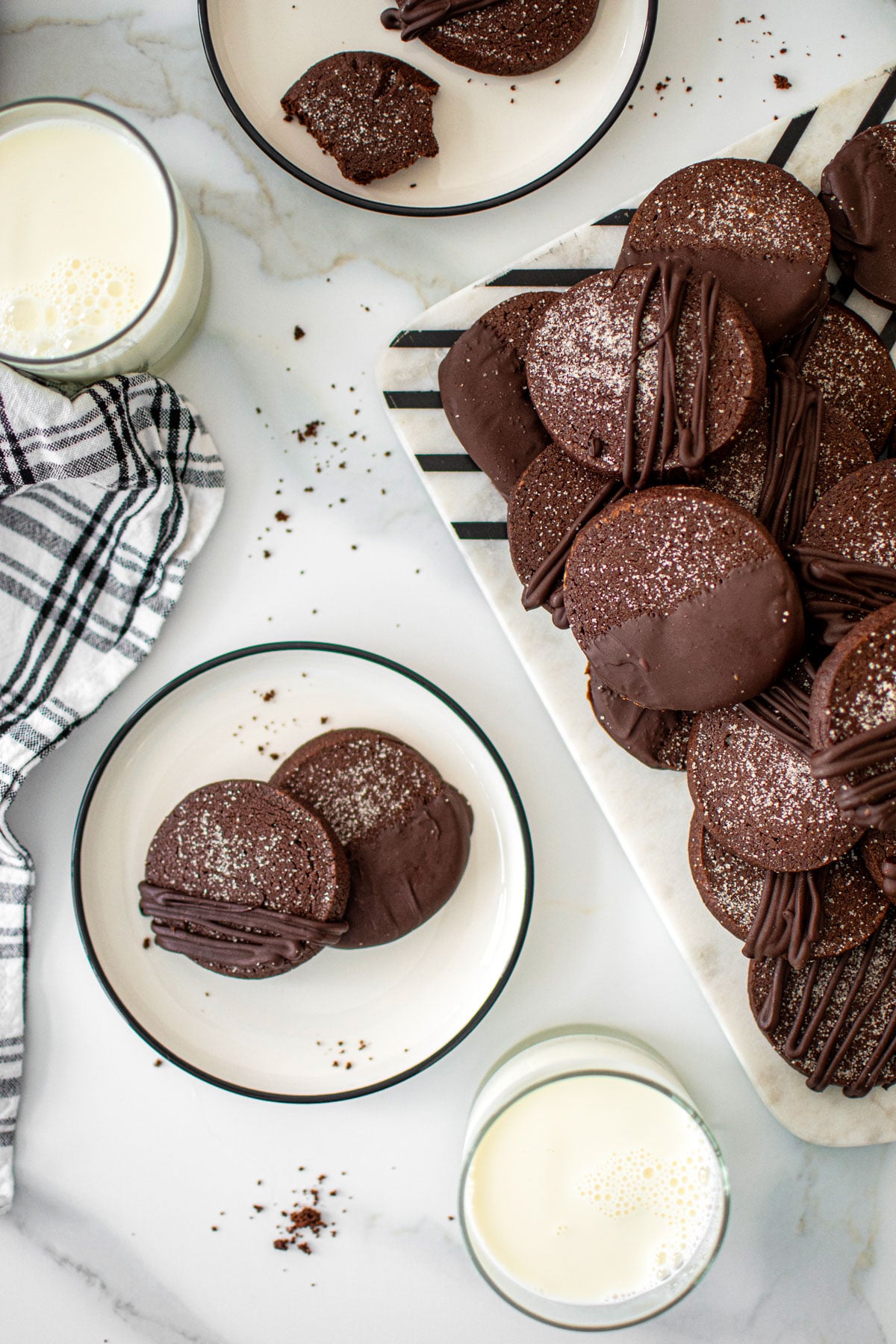 sourdough chocolate shortbread cookies on a plate on a marble counter with a glass of milk.