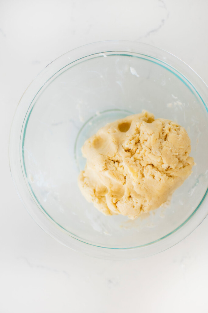 sourdough discard pie crust in a glass mixing bowl on a white marble counter.