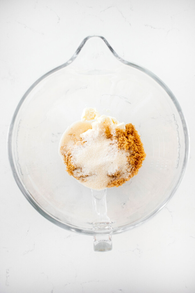 shortening and sugar in a glass mixing bowl on a white countertop.
