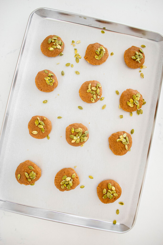vegan pumpkin spice almond butter cookie dough balls on a baking sheet.