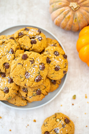 gluten free pumpkin chocolate chip cookies on a plate with pumpkins in background.