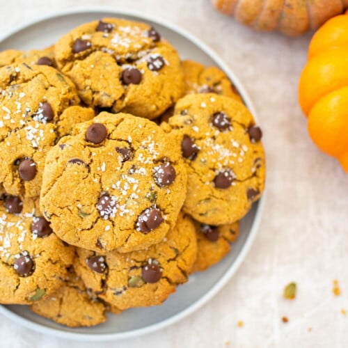 gluten free pumpkin chocolate chip cookies on a plate with pumpkins in background.