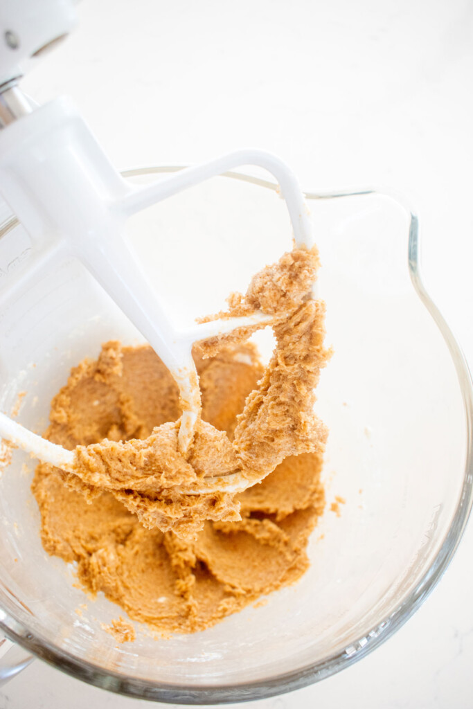 creamed butter and sugar in a glass mixing bowl on a white marble counter.