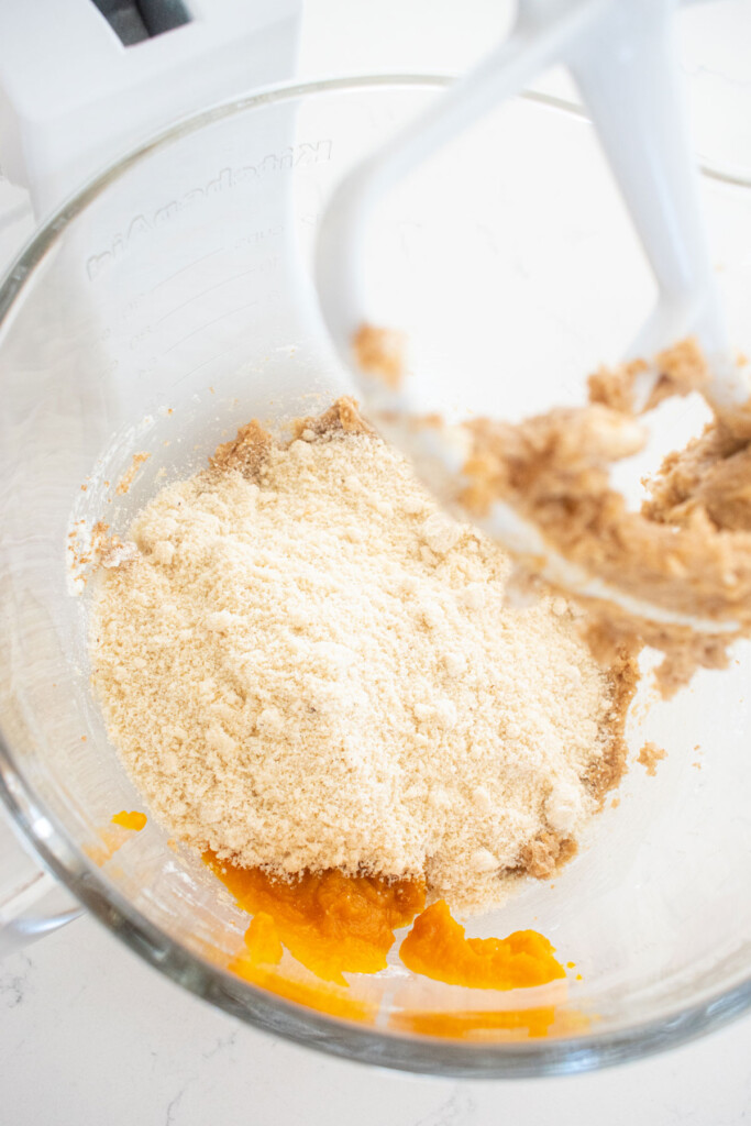 ingredients for gluten free pumpkin chocolate chip cookies in a glass mixing bowl on a white counter.