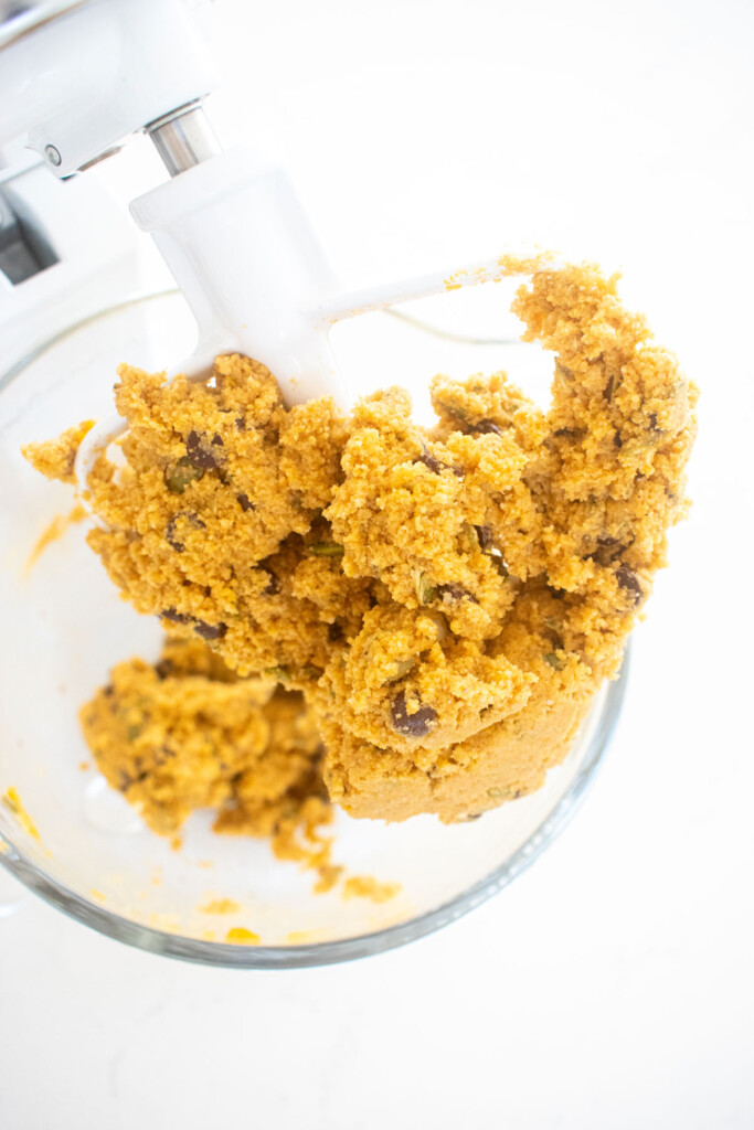 gluten free pumpkin chocolate chip cookie dough in a glass mixing bowl on a white marble counter.
