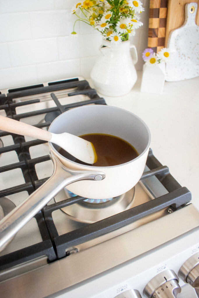 small pot with wet ingredients being cooked for chocolate olive oil granola on a stovetop.