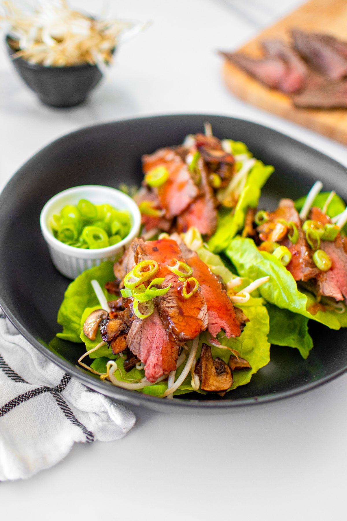 flank steak asian lettuce wraps in a black bowl on a white marble countertop.