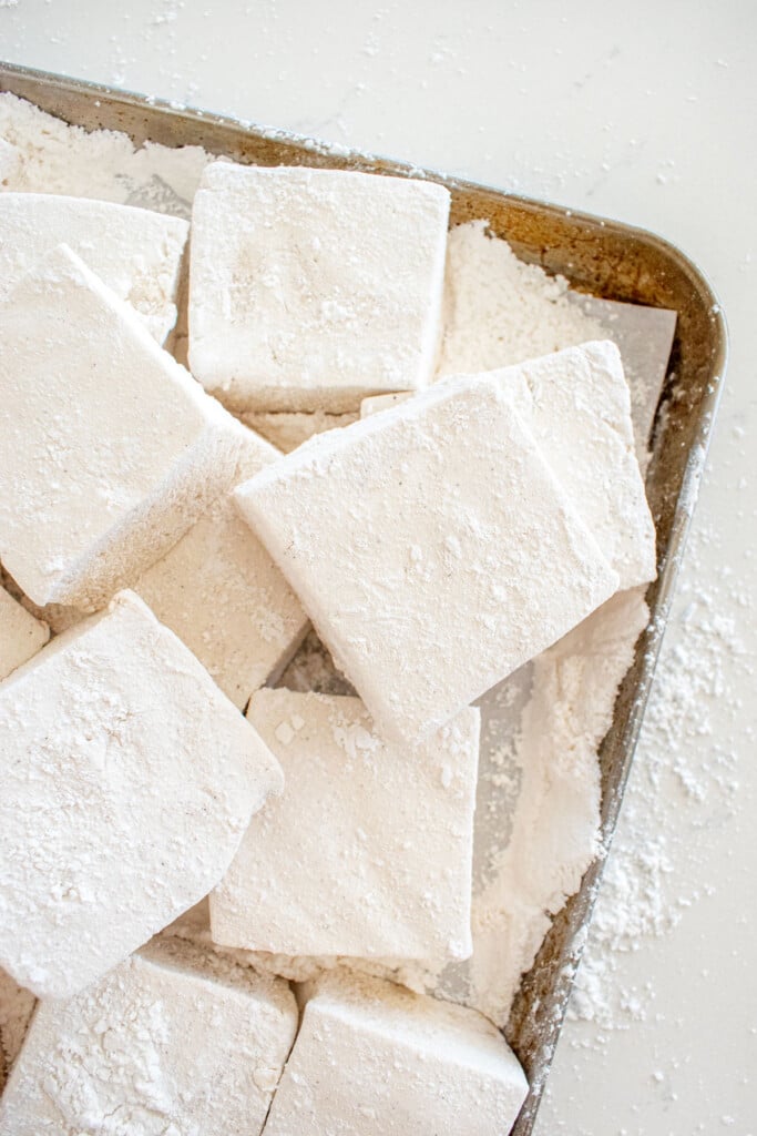 baking sheet with homemade marshmallows cut into large squares on a marble counter.