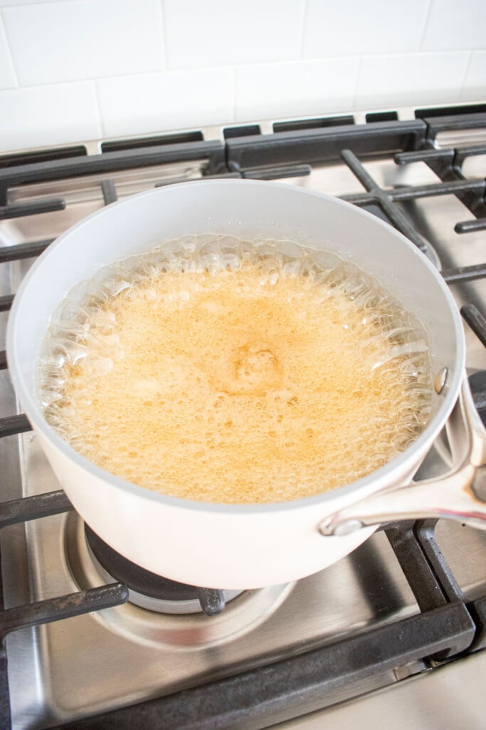 ingredients for homemade marshmallows bubbling up in a pot on the stovetop.