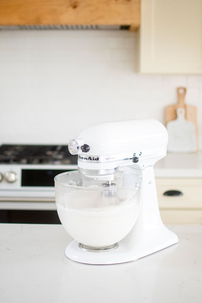 stand mixer mixing homemade marshmallows on a kitchen counter.