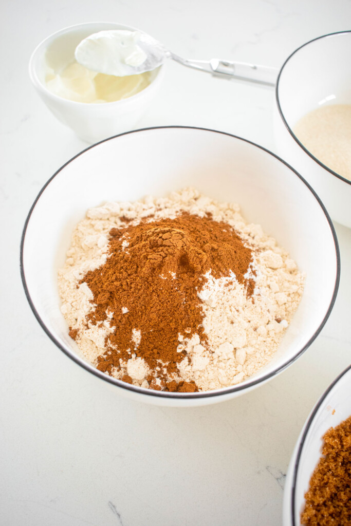 dry ingredients for pumpkin spice baked donuts in a white bowl on a marble counter.