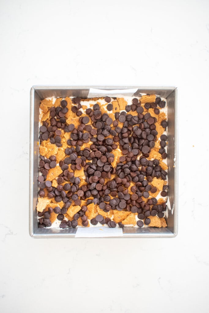 pumpkin spice smore bar dough with marshmallow graham crackers and chocolate chips in a baking pan.