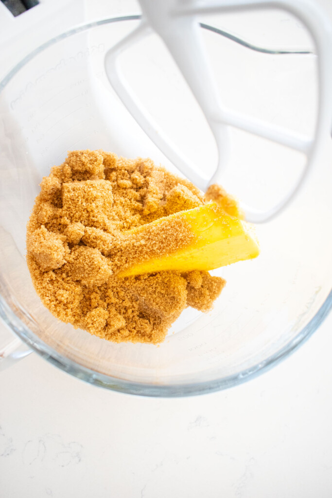 brown sugar and butter in a glass mixing bowl on a white marble counter.