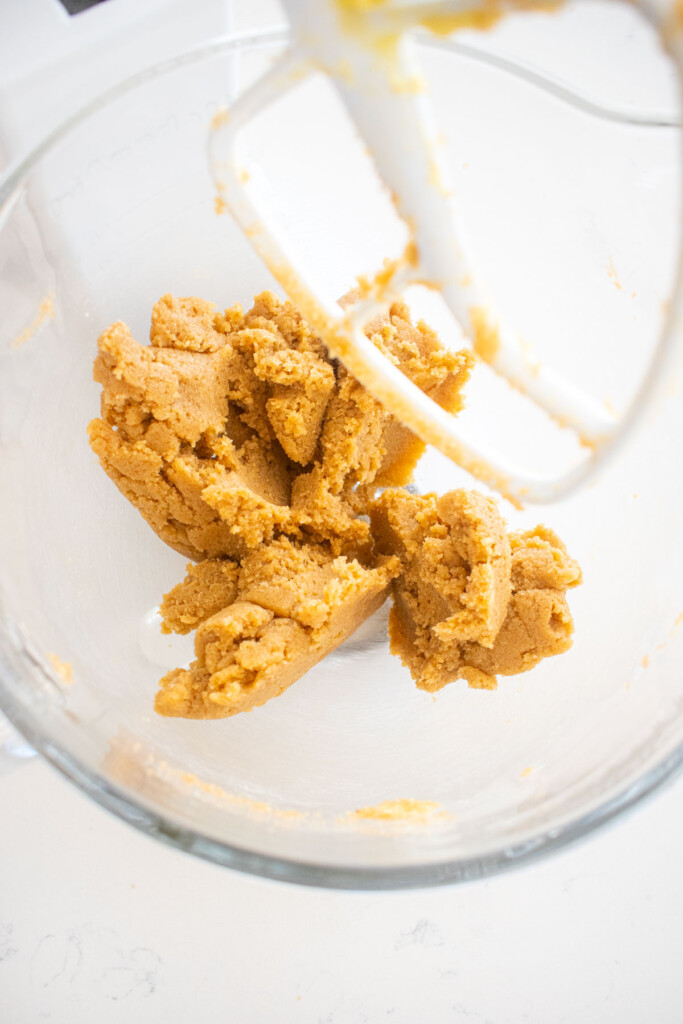 creamed brown sugar and butter in a glass mixing bowl on a white marble counter.