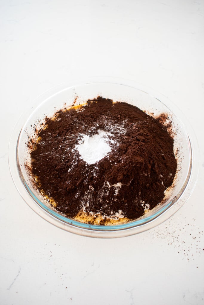 ingredients for spooky rose halloween cake in a glass mixing bowl on a white marble counter.