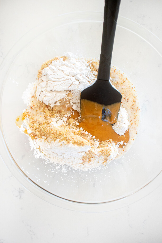 ingredients for peanut butter filling in a glass mixing bowl on a white marble counter.