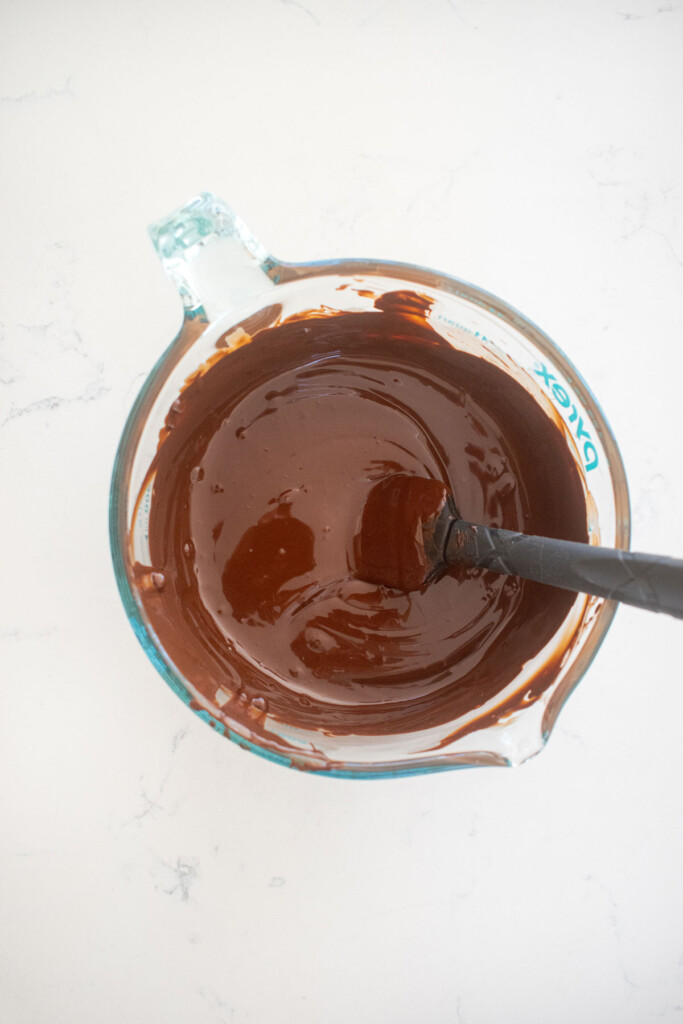 melted chocolate in a pyrex measuring cup on a white marble counter.