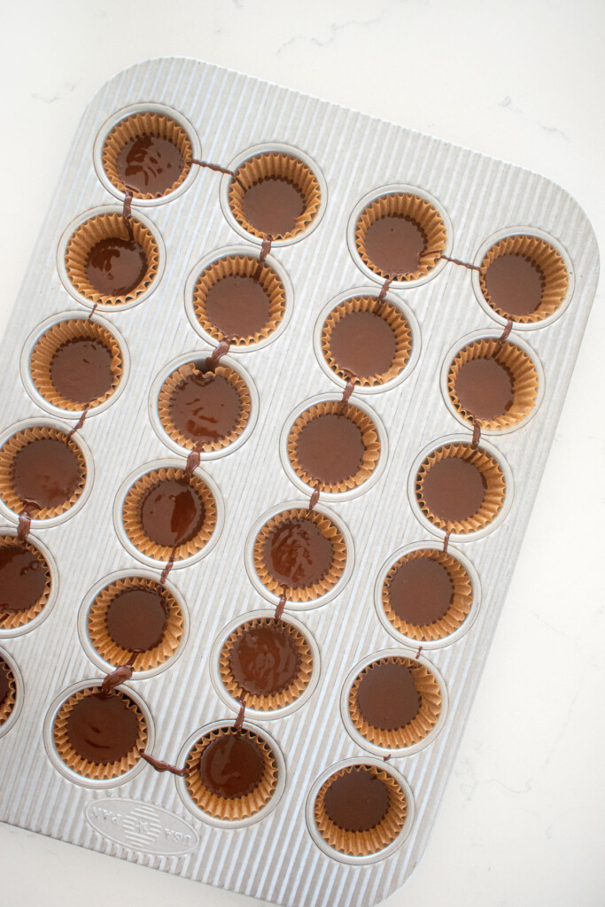 melted chocolate in a mini muffin pan on a white marble counter.