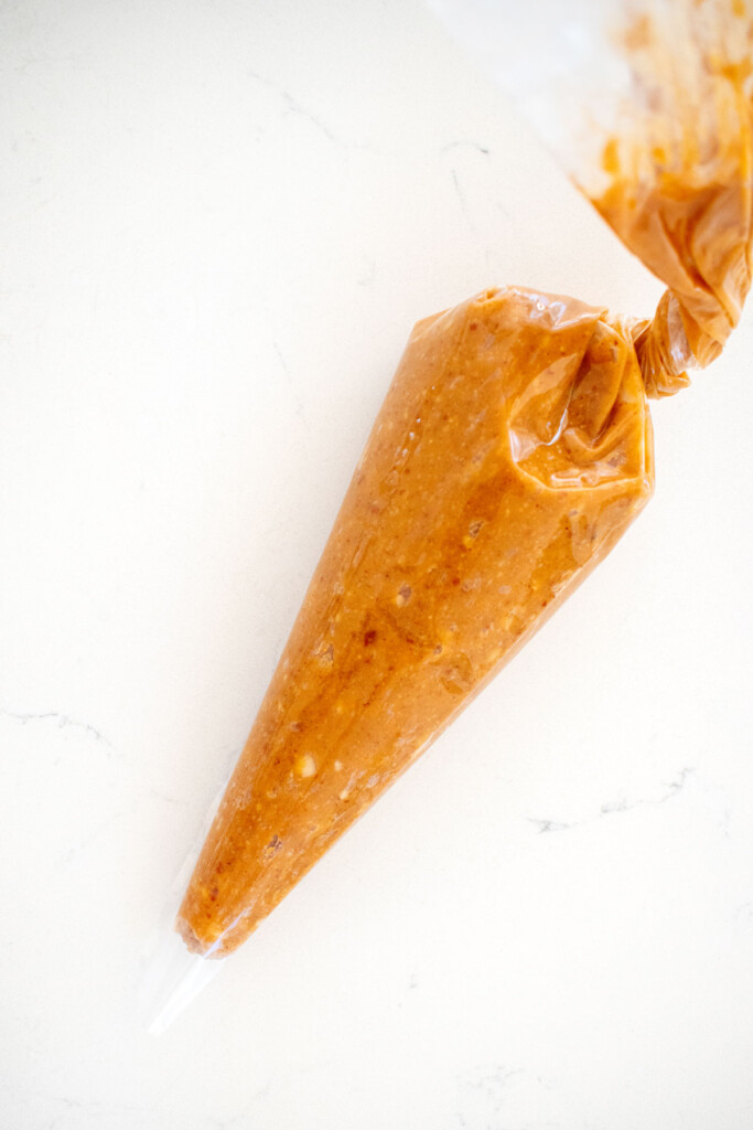peanut butter filling in a piping bag on a white marble counter.