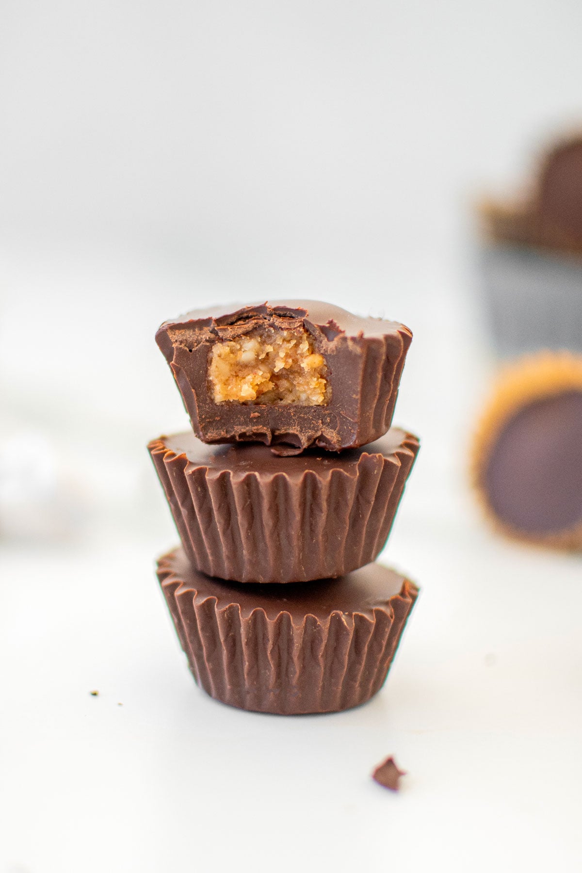 stack of three vegan dark chocolate mini peanut butter cups on a white marble counter.