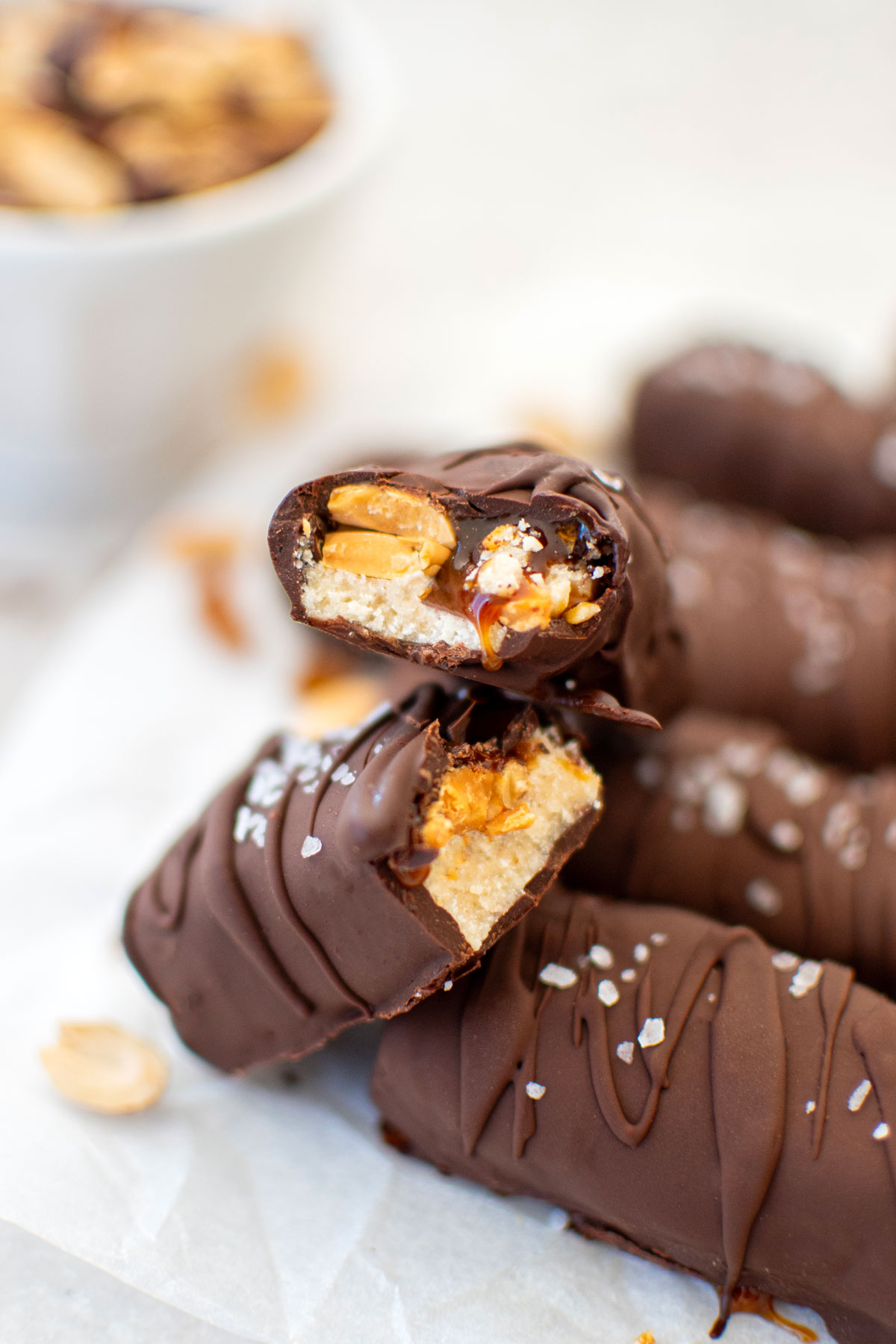 vegan snickers bar cut in half with caramel oozing out on a marble board.