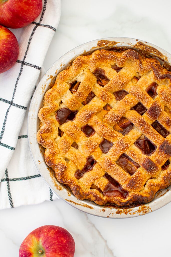 brown sugar honey apple pie in a aluminum pie pan on a white marble counter.
