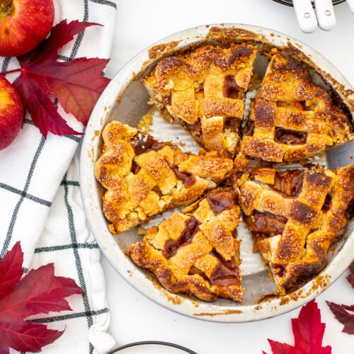 brown sugar honey apple pie sliced in a aluminum pie pan on a white marble counter.